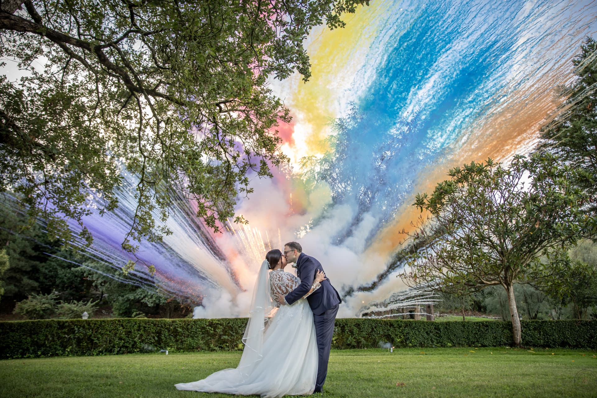 Wanda and Alberto embracing beneath colorful wedding fireworks