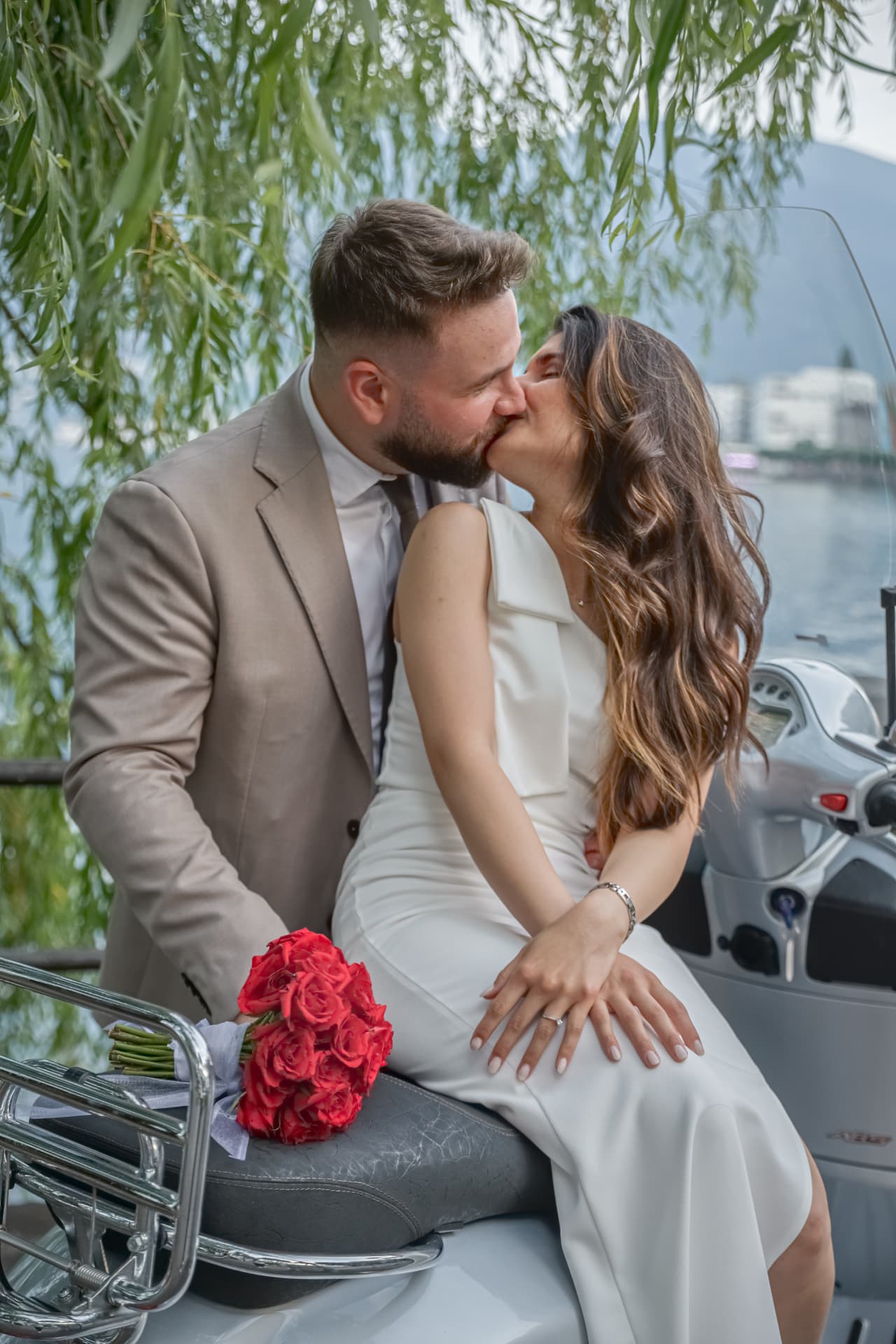 Newlyweds kissing on a vintage Vespa