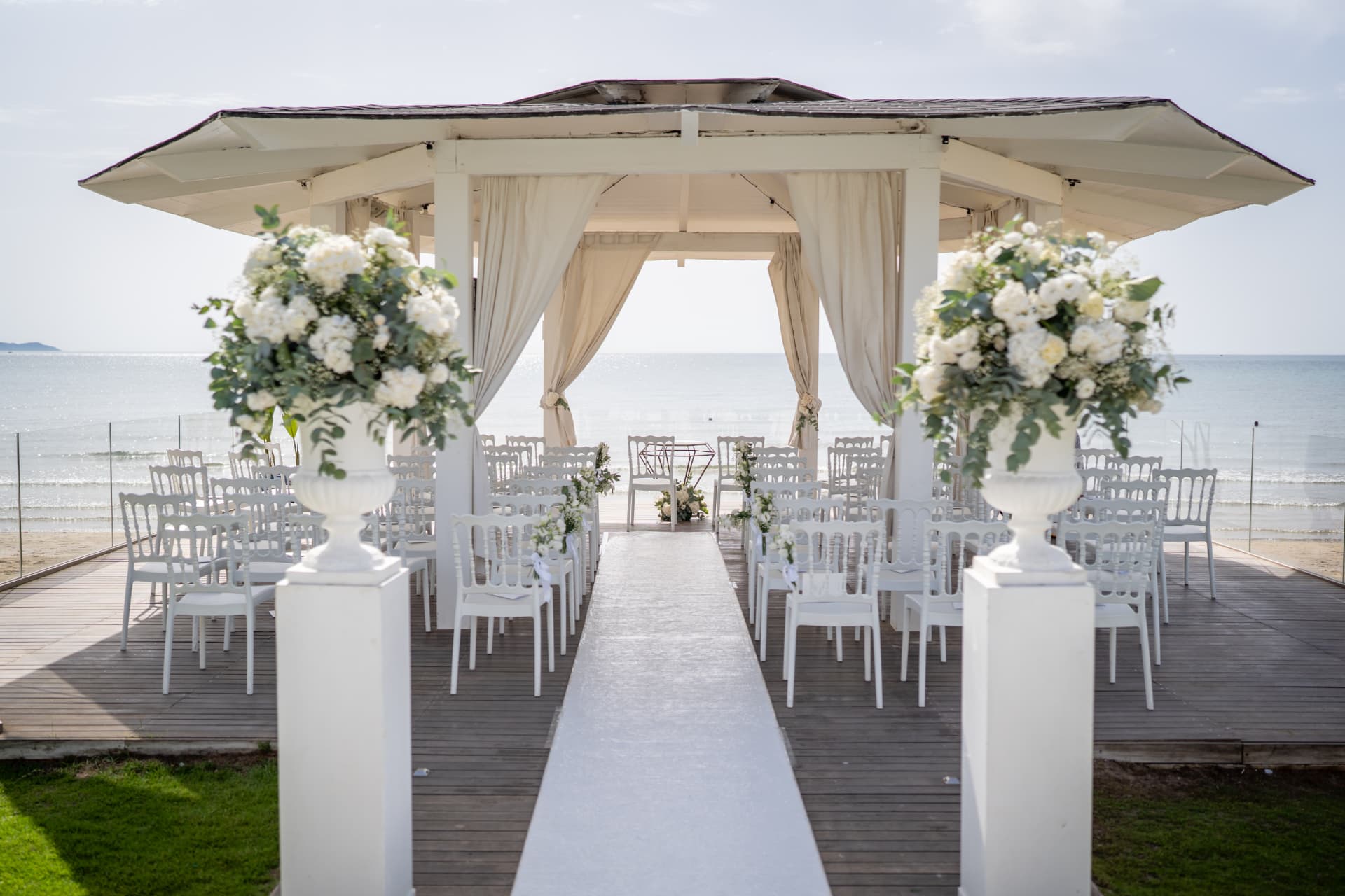 Seaside ceremony gazebo with white flowers and rows of chairs
