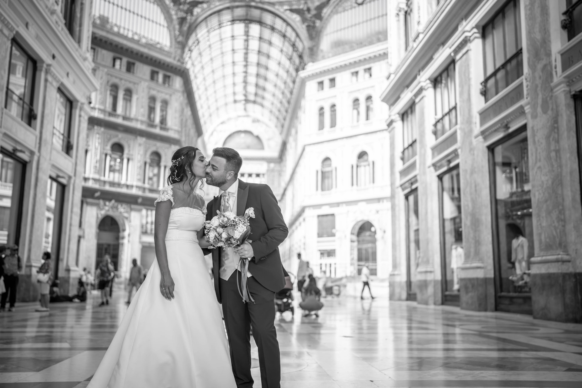 Newlyweds kissing beneath the glass arcade