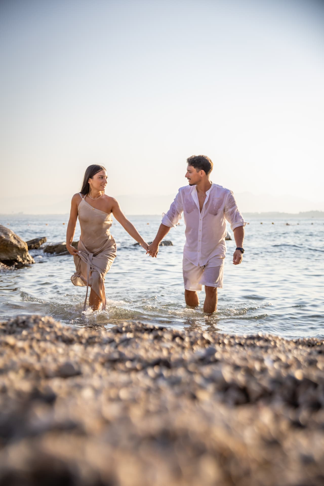 Couple walking hand in hand in the shallow water at sunset