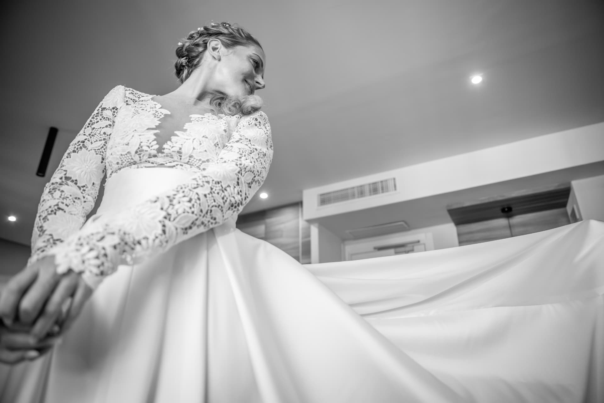 Black and white portrait of a bride arranging her gown
